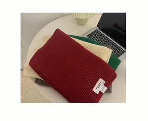 Close-up of thick knitted winter scarves in multiple colors on a cozy desktop