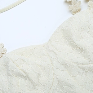 Detail view of intricate cream crochet lace fabric with 3D floral embroidery applique