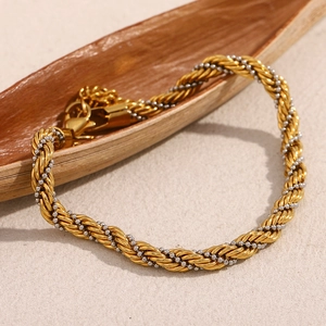 Détail d'un bracelet torsadé bicolore or et argent avec fermoir mousqueton sur bois