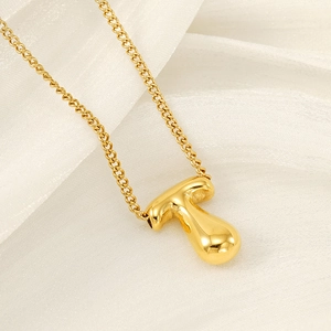 Polished gold bubble letter T pendant necklace on silk background for women