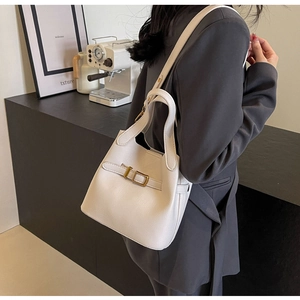 Detailed macro of white bucket bag with lychee grain texture and gold metal buckle
