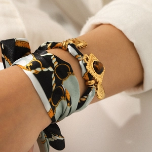 Golden chain bracelet with a silk scarf, sun charm, gemstone, and LOVE heart pendant