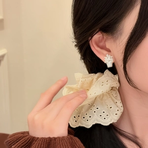 Close-up detail of 18k gold plated zircon flower basket pearl earrings worn by model