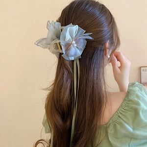 Detail of light green organza bow hair claw clip with double pearls on elegant hairstyle
