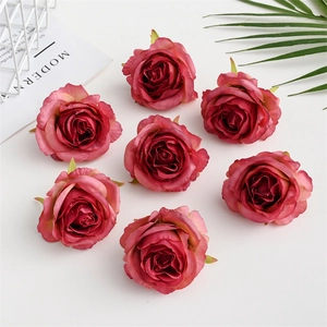 Flat lay of seven deep pink silk rose heads on white table for wedding floral decor