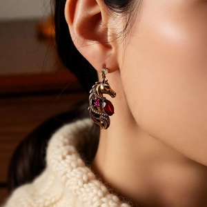 Close-up of vintage horse head earrings with red drop gemstones and small pink diamonds