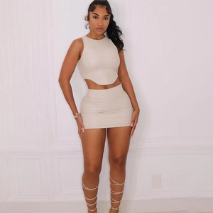 Dettaglio di un completo beige in pelle PU con top corto e minigonna a tubino aderente