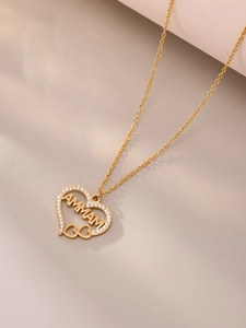 Gedetailleerd beeld van een gouden hartvormige hanger met AMMAM-letters en kristallen