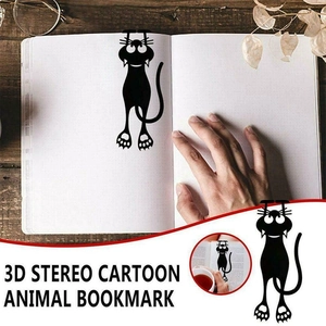 Detail of 3D cartoon black cat bookmark in a book on a vintage wooden desk