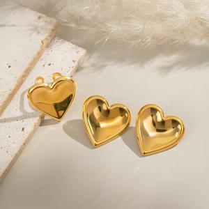 Detailed view of polished heart-shaped gold earrings set on a marble surface