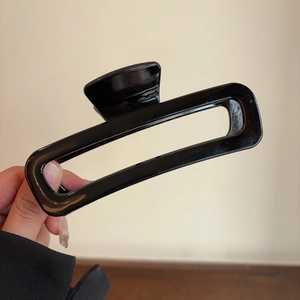 Close-up of large glossy black acetate hair claw clip with rectangular hollow design