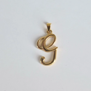 Vue macro d'un pendentif monogramme lettre g en acier inoxydable plaqué or 18 carats