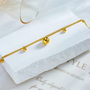 Minimalist gold plated stainless steel bead charm anklet on a white stone base