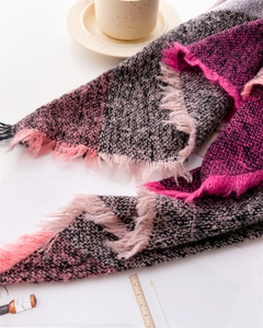 Flat lay detail of pink and grey plaid cashmere-like scarf with fringe accents and decor