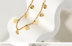 Macro detail of 18K gold-plated beaded anklet with radial textured petal pendants