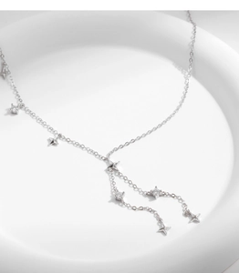 Macro detail of silver S925 star tassel Y-necklace with cubic zirconia on white display
