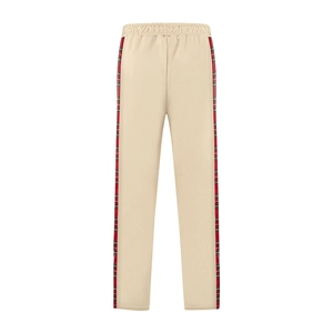 Detail of beige casual pants featuring side red plaid stripes and elastic waistband