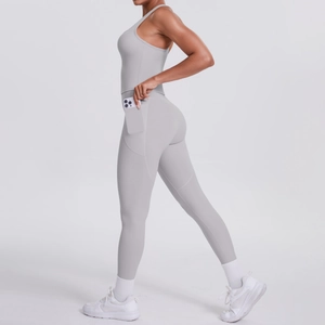 Close-up of functional side pocket on light grey yoga jumpsuit holding a smartphone