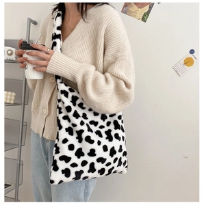Close-up of fluffy black and white cow print plush shoulder bag with soft faux fur texture