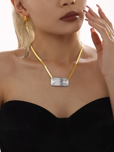 Detailed close-up of mixed-metal necklace with gold snake chain and silver textured pendant