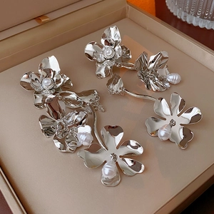Detailed close-up of silver flower earrings with pearls on a satin jewelry box cushion