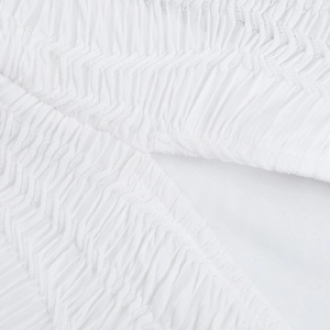 Macro shot of white pleated fabric texture and ruched material on backless maxi dress