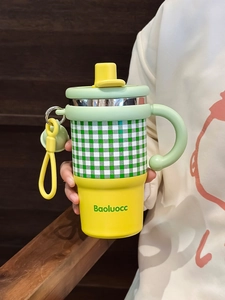 Close-up of yellow and green checkered stainless steel insulated mug with handle and strap