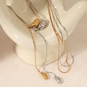 Irregular geometric bean pendant necklace in gold and silver finish on display stand