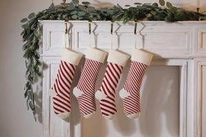 Detail of red and white striped knit Christmas stockings hanging on a white wooden mantel