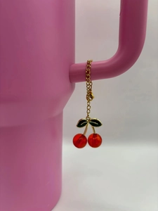 Detail view of red cherry charm with gold chain on pink tumbler handle accessory