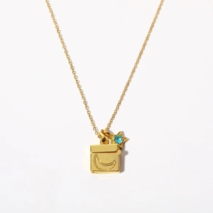 Detailed macro view of gold star and moon locket necklace with light blue gemstone