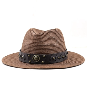 Detail of western straw hat with leather band and brass studs on a dark brown surface