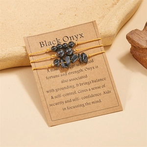 Three-piece set of black onyx woven bracelets displayed on an informative kraft paper card
