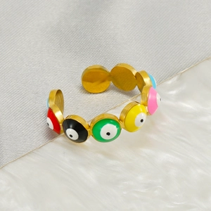 Macro detail of golden evil eye ring showing colorful enamel beads on a textured surface