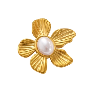 Detailed macro view of a golden flower brooch with matte texture and a central pearl