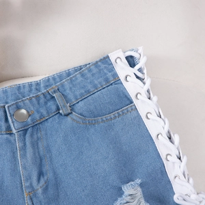 Dettaglio degli shorts in denim blu con lacci laterali bianchi e occhielli metallici
