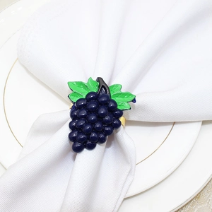 Macro view of blue grape enamel napkin ring with golden metal loop on white plate