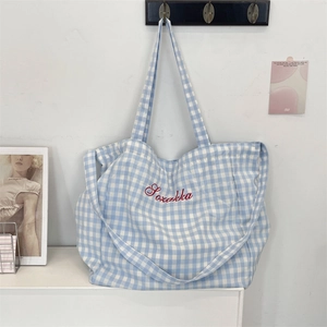 Detail of blue plaid canvas tote bag featuring red Szakka embroidery and spacious design