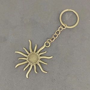Vintage bronze sun pendant keychain with metal ring and chain on grey concrete background