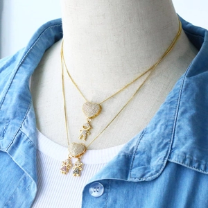 Detail of layered gold heart necklace featuring boy and girl charms on a model