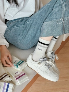 Detail of white cotton athletic socks featuring Smile embroidery and striped ribbing