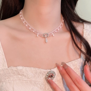 Macro detail of pink crystal beaded choker featuring lace texture and white flower accents