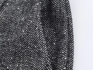 Detailed macro view of black and white herringbone pattern on tweed blazer fabric