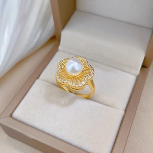 Macro shot of gold-plated flower ring with center pearl and sparkling crystals in a box