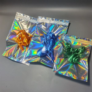 Three 3D printed animal figures in colorful holographic bags, orange frog and green crab