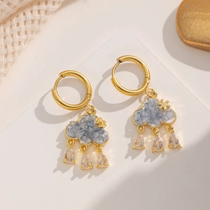 Detail of cloud-shaped gold earrings with blue stones and clear teardrop crystals