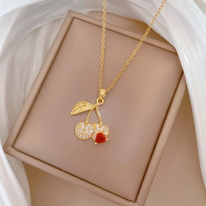 Detail of gold cherry necklace with red gemstone and diamonds in a luxury gift box