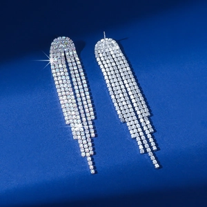 Macro shot of long silver tassel earrings with iridescent rhinestones on blue background