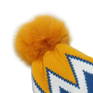 Dettaglio macro del pompon soffice e della trama a maglia su un berretto invernale giallo