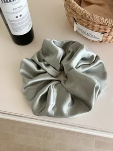 Detailed texture of sage green oversized satin scrunchie with elegant silk luster